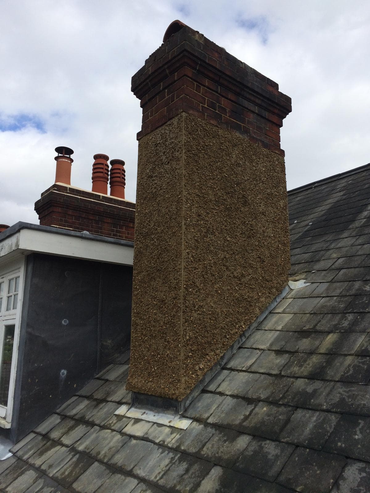 Lead-covered bay roof with welded rolls running down to a drip, above a painted stone cornice