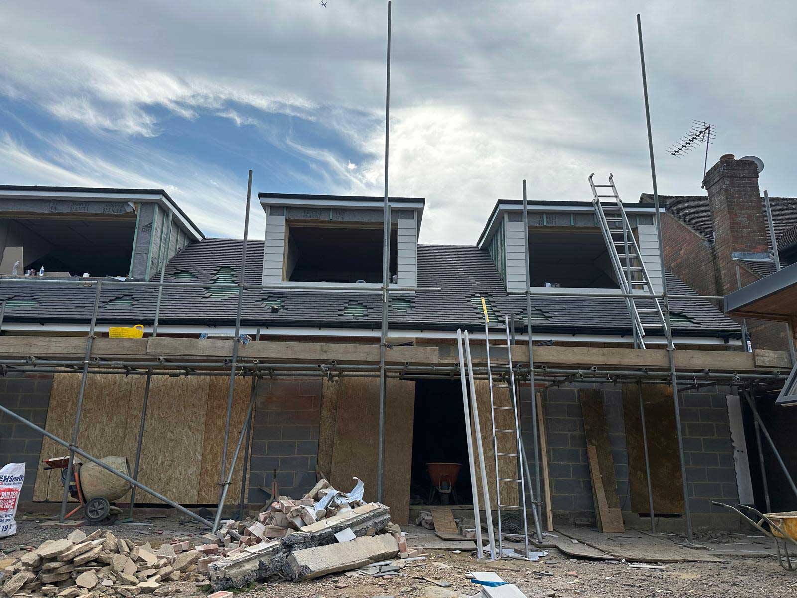 Finished clay plain tile roof in blended reds with a clay half-round ridge and a small tiled dormer below