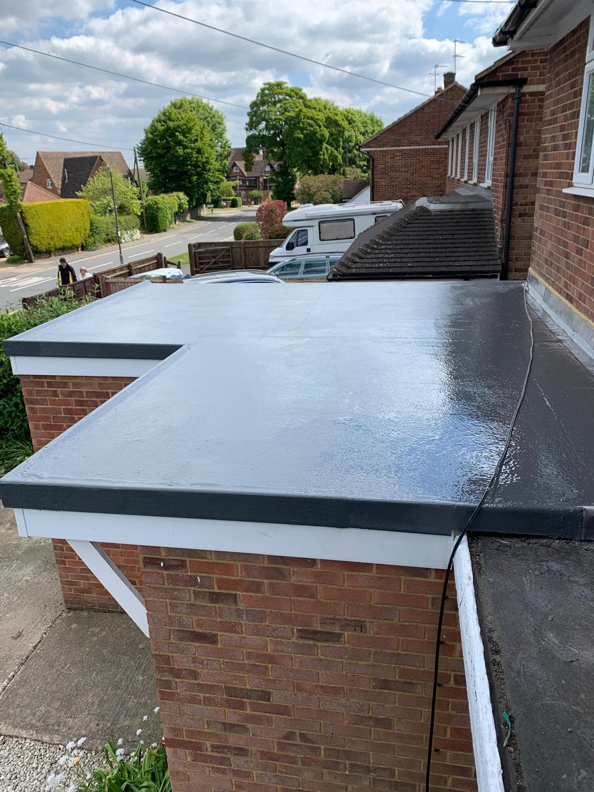Finished grey GRP fibreglass balcony roof with continuous upstands, flower boxes on the railing behind