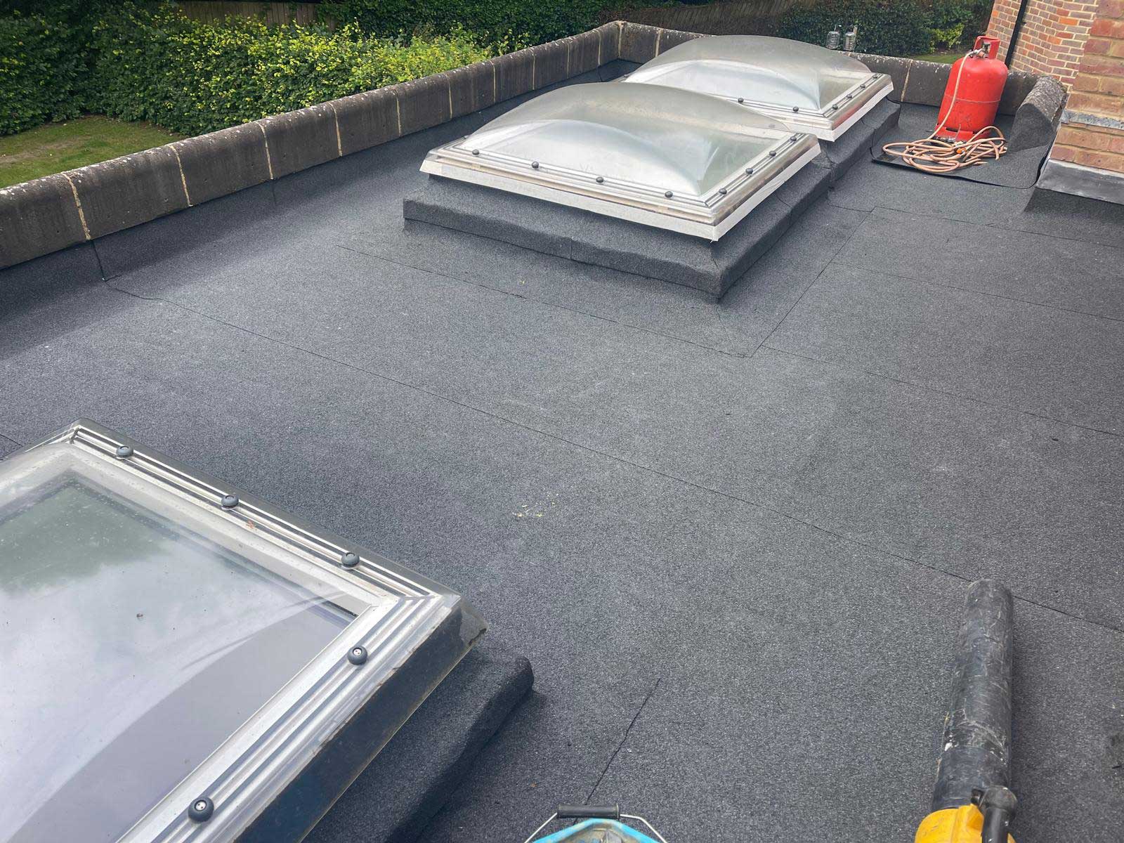 Finished grey GRP fibreglass balcony roof with continuous upstands, flower boxes on the railing behind