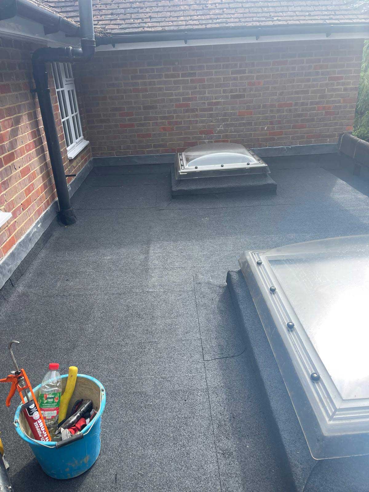 Finished grey GRP fibreglass balcony roof with continuous upstands, flower boxes on the railing behind