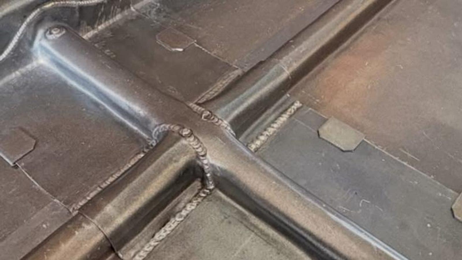 Lead flat roof with welded rolls meeting at a T-junction, dressed up to an old brick wall