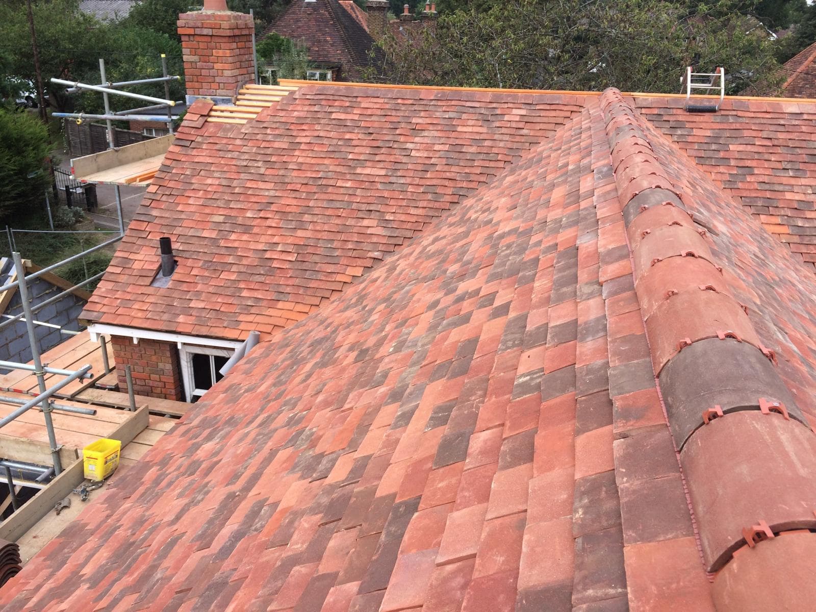 Finished clay plain tile roof in blended reds with a clay half-round ridge and a small tiled dormer below