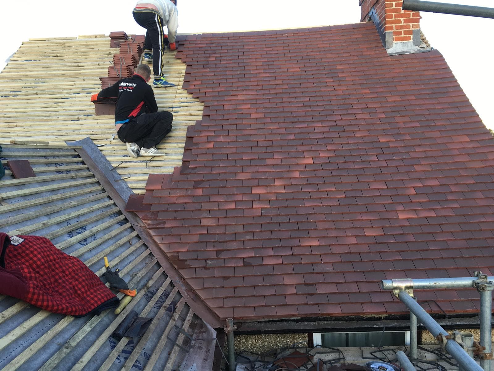 Finished clay plain tile roof in blended reds with a clay half-round ridge and a small tiled dormer below